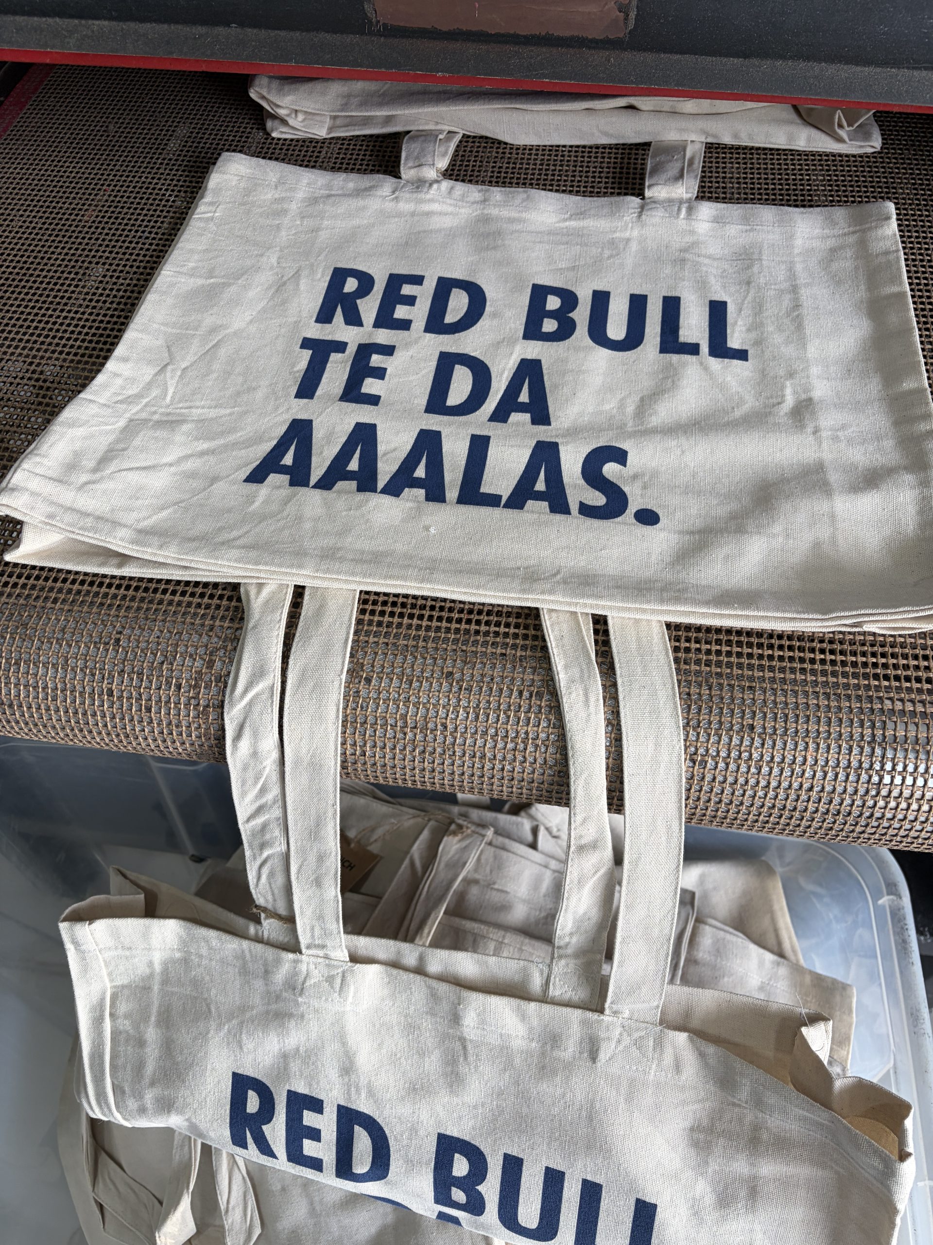 Bolsas de tela con impresión azul sobre la cinta de secado del taller
