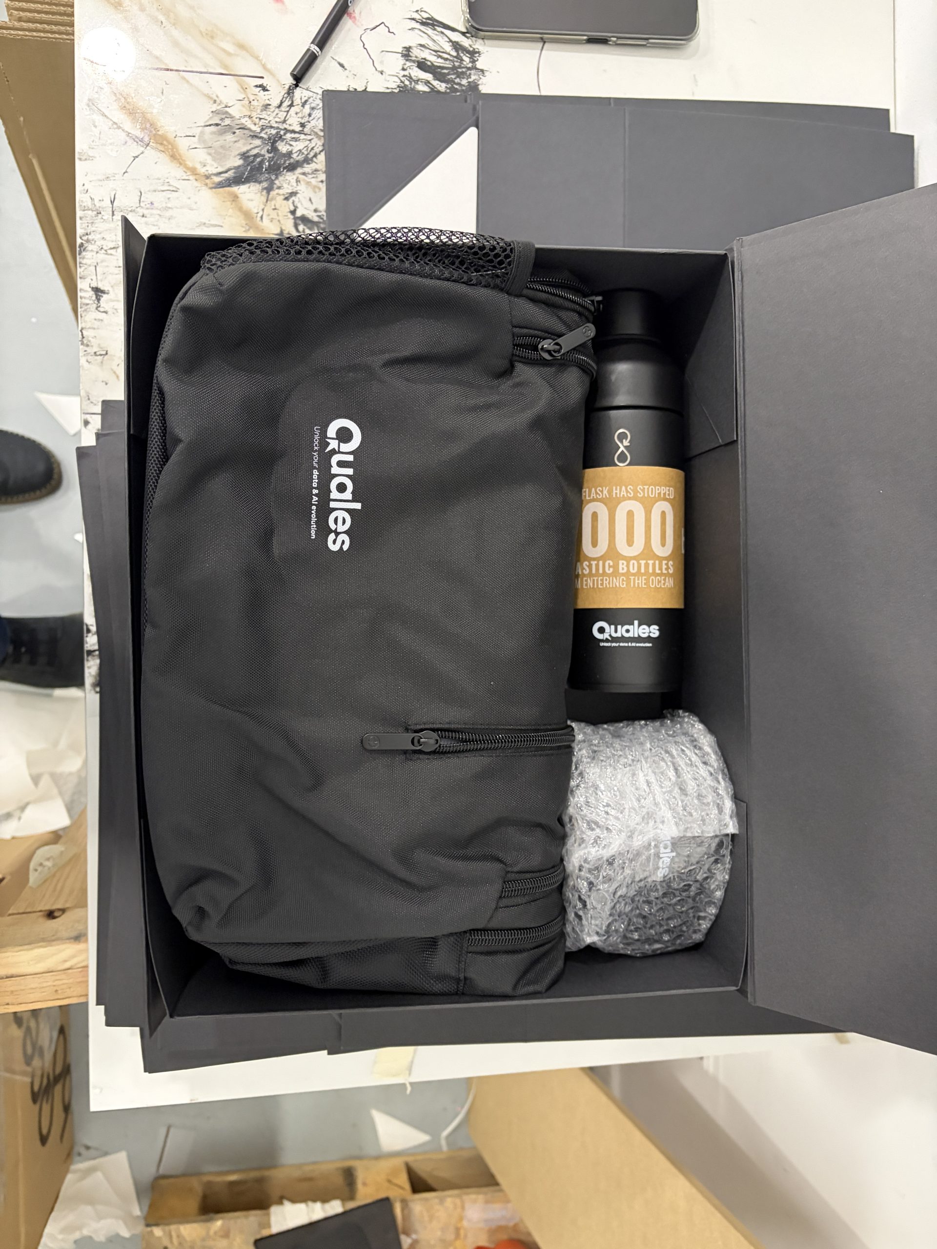 Kit de bienvenida con mochila negra y botella personalizada presentado en una caja